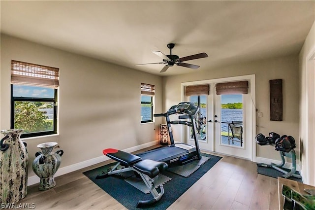 workout room featuring hardwood / wood-style flooring, a water view, plenty of natural light, and french doors