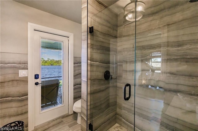 bathroom featuring a shower with shower door and toilet