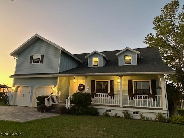 view of front of house featuring a lawn, a porch, and a garage