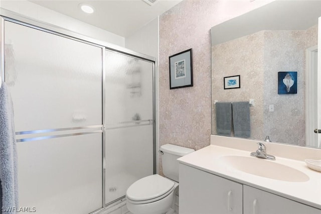 bathroom with vanity, toilet, and a shower with shower door