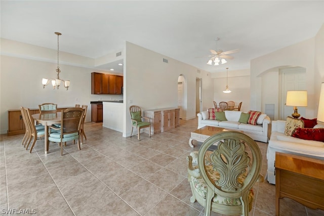 tiled living room featuring ceiling fan with notable chandelier