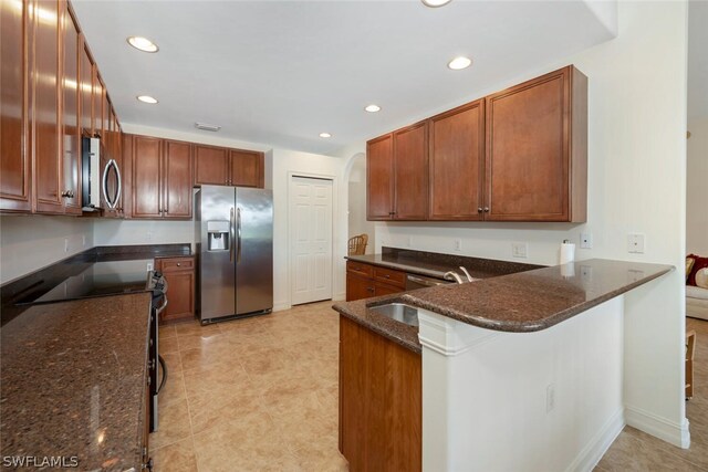 kitchen with kitchen peninsula, sink, dark stone countertops, and appliances with stainless steel finishes