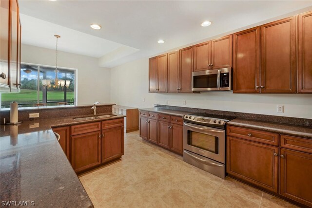 kitchen featuring appliances with stainless steel finishes, sink, an inviting chandelier, dark stone countertops, and hanging light fixtures