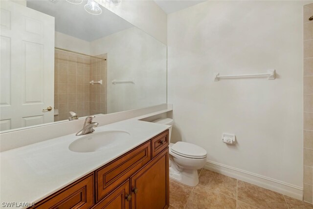 bathroom with toilet, a tile shower, vanity, and tile patterned floors