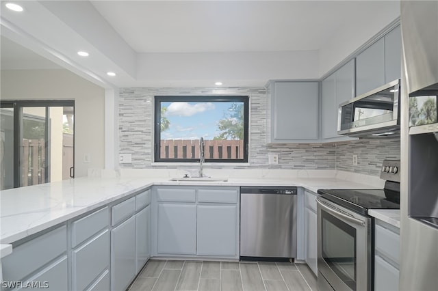 kitchen featuring a wealth of natural light, stainless steel appliances, light stone counters, and sink