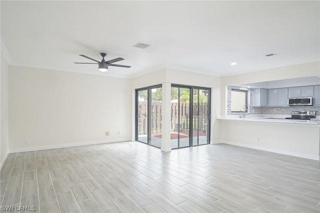 unfurnished living room featuring ceiling fan, sink, and ornamental molding