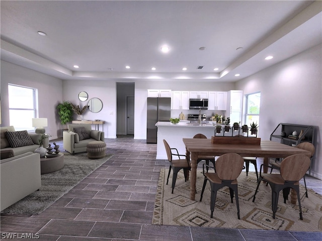 dining space featuring dark tile flooring and a raised ceiling