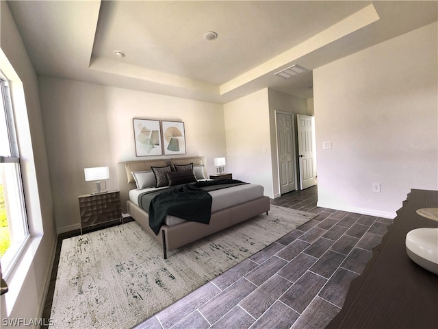 bedroom with a tray ceiling and hardwood / wood-style floors