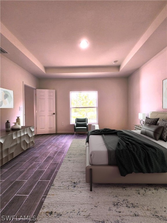 bedroom with dark wood-type flooring and a tray ceiling