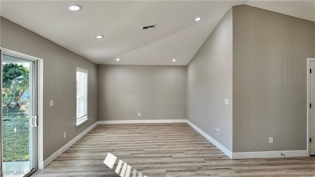 spare room featuring light hardwood / wood-style flooring, a healthy amount of sunlight, and vaulted ceiling