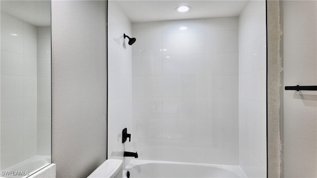 bathroom featuring tiled shower / bath combo and toilet