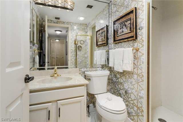 bathroom featuring a tile shower, vanity, and toilet