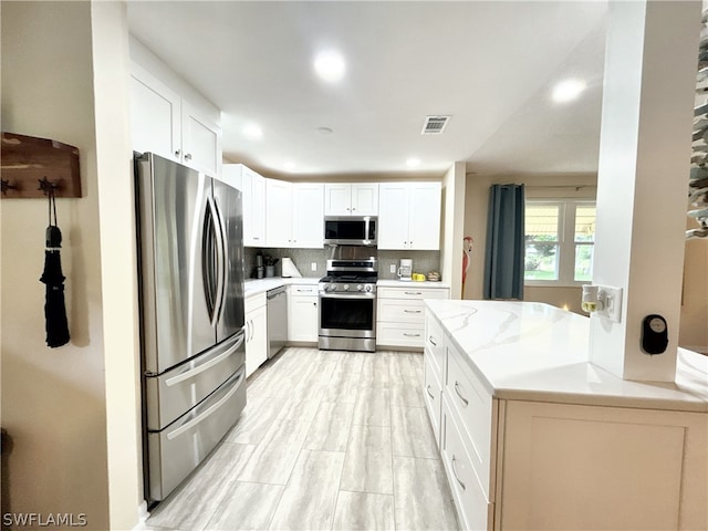 kitchen with white cabinetry, tasteful backsplash, kitchen peninsula, and stainless steel appliances