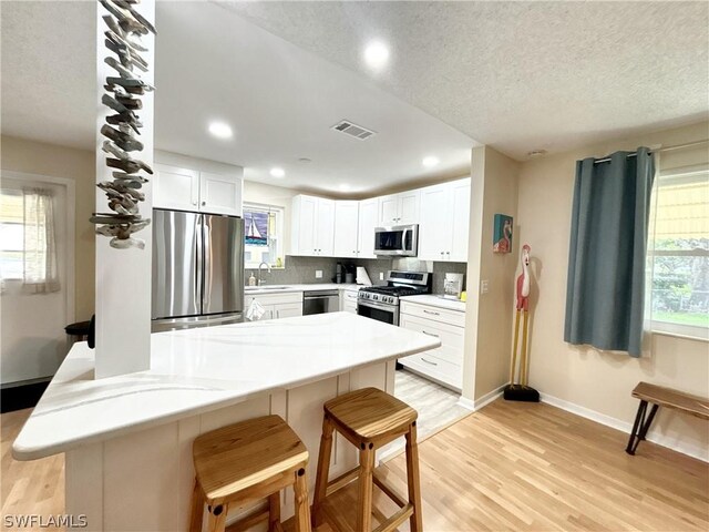 kitchen featuring appliances with stainless steel finishes, sink, a kitchen breakfast bar, and light wood-type flooring