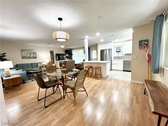 dining area with a textured ceiling and light wood-type flooring