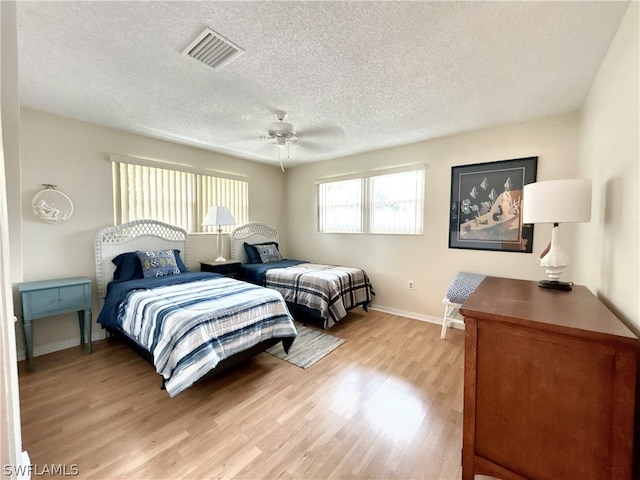 bedroom with a textured ceiling, ceiling fan, and hardwood / wood-style floors