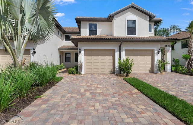 mediterranean / spanish house with a tile roof, decorative driveway, and stucco siding