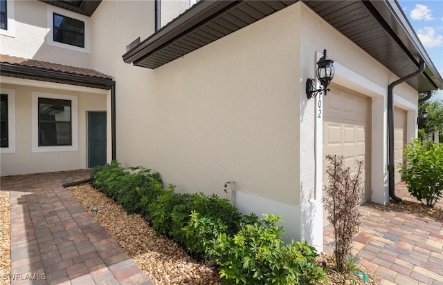 view of side of home featuring an attached garage and stucco siding