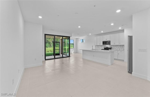 kitchen with recessed lighting, decorative backsplash, appliances with stainless steel finishes, open floor plan, and white cabinets