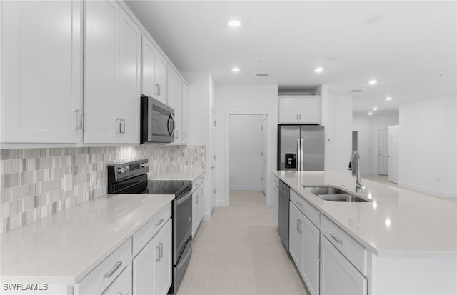 kitchen featuring light tile patterned floors, appliances with stainless steel finishes, light stone countertops, white cabinetry, and sink