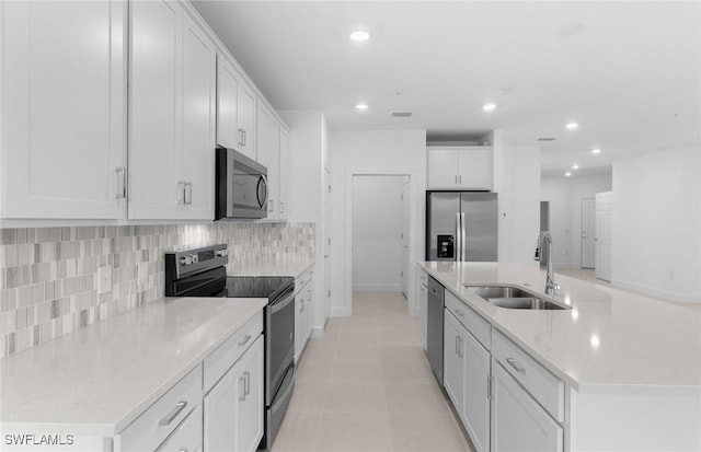 kitchen with tasteful backsplash, an island with sink, stainless steel appliances, a sink, and recessed lighting