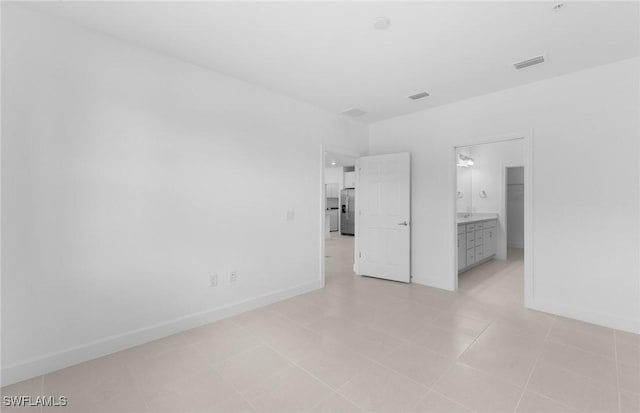 unfurnished bedroom with baseboards, visible vents, and stainless steel fridge with ice dispenser