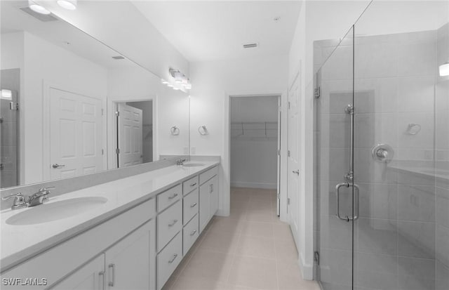 full bathroom featuring double vanity, a stall shower, tile patterned flooring, and a sink