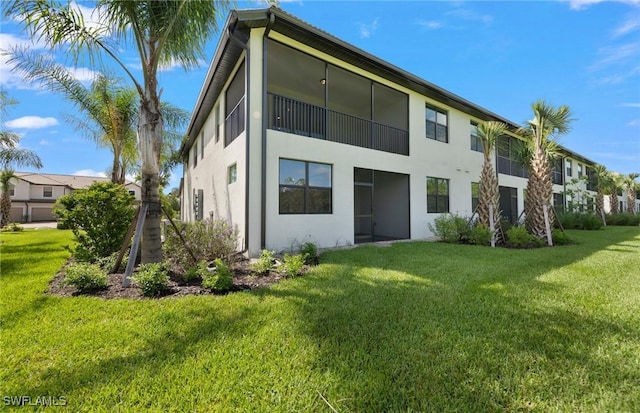 back of property with a lawn and stucco siding