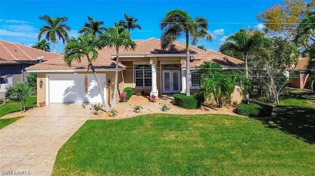 mediterranean / spanish home with a front yard, french doors, and a garage