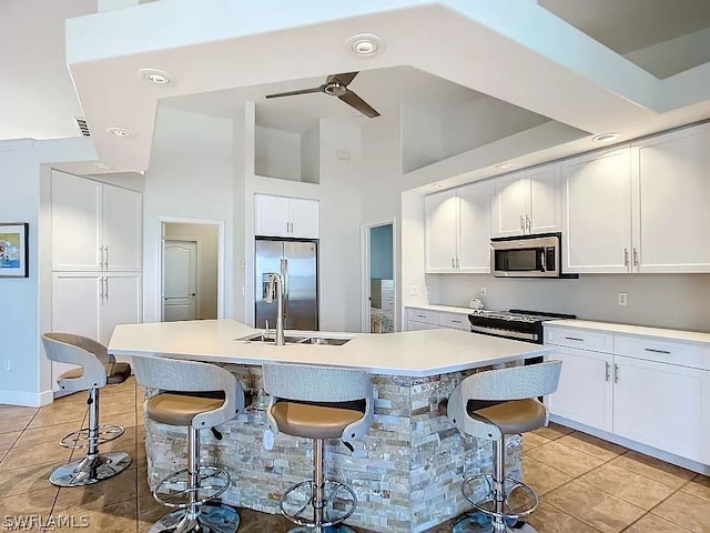 kitchen featuring a breakfast bar area, a kitchen island with sink, white cabinets, and appliances with stainless steel finishes