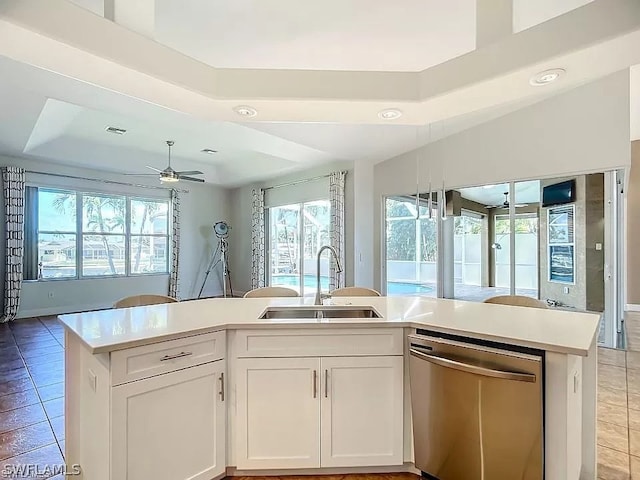 kitchen featuring stainless steel dishwasher, a tray ceiling, ceiling fan, sink, and white cabinets