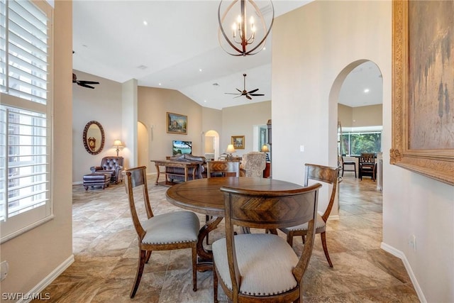 dining room featuring ceiling fan with notable chandelier and vaulted ceiling