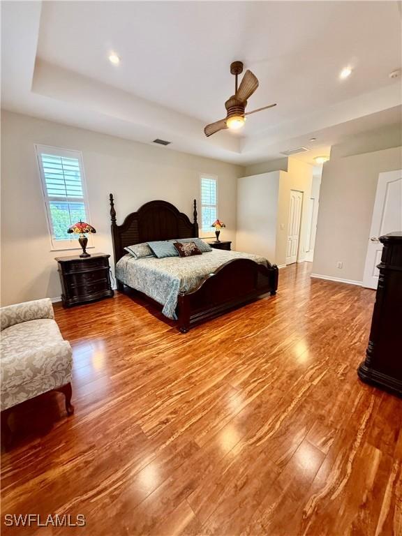 bedroom featuring ceiling fan, a raised ceiling, and hardwood / wood-style flooring