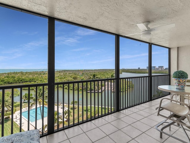 unfurnished sunroom featuring a water view and ceiling fan