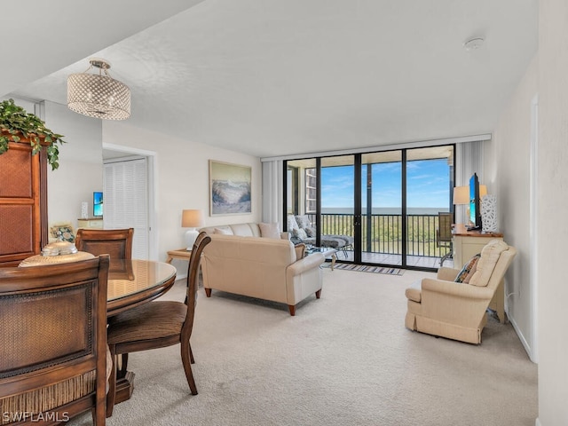 living room featuring expansive windows, light carpet, and a notable chandelier