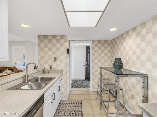 kitchen featuring light tile patterned floors, dishwasher, sink, and white cabinets