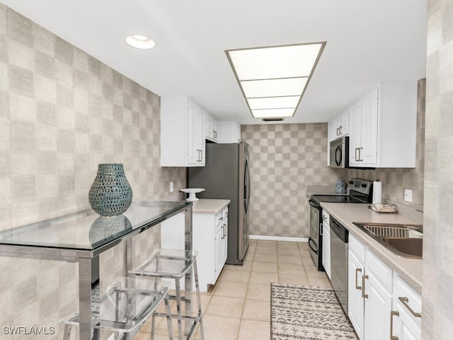 kitchen with white cabinetry, sink, light tile patterned flooring, and appliances with stainless steel finishes