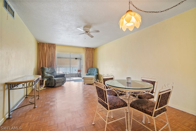 dining space featuring ceiling fan, a textured ceiling, and parquet floors