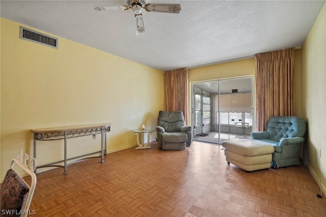 sitting room featuring a textured ceiling, ceiling fan, and parquet flooring