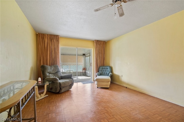 sitting room with parquet flooring, ceiling fan, and a textured ceiling