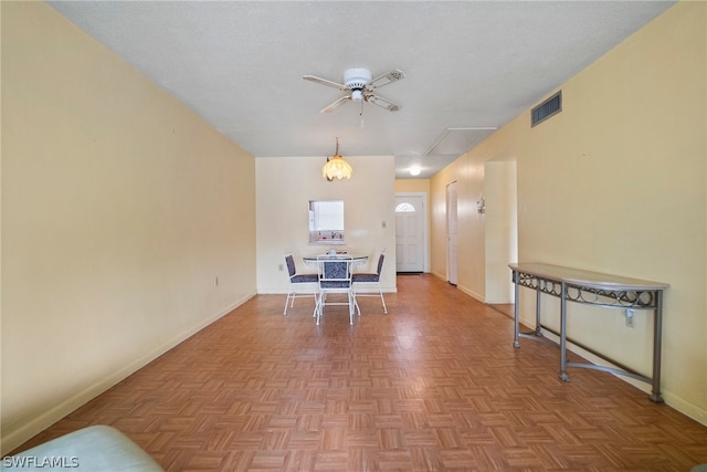 interior space with parquet flooring, ceiling fan, a textured ceiling, and pendant lighting