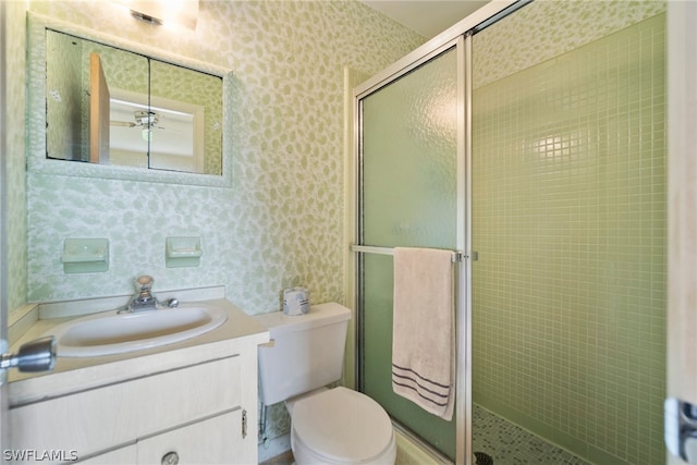 bathroom with a shower with door, toilet, ceiling fan, and oversized vanity