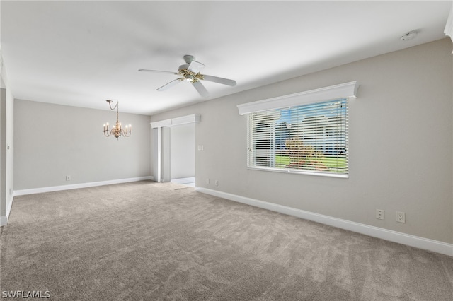 spare room with carpet and ceiling fan with notable chandelier