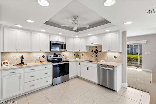 kitchen featuring white cabinets, a raised ceiling, sink, and appliances with stainless steel finishes