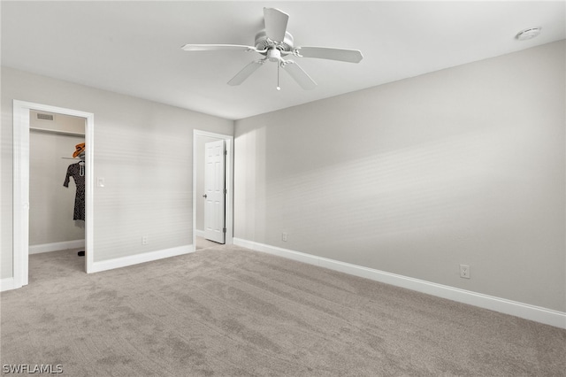 unfurnished bedroom with ceiling fan, a walk in closet, light carpet, and a closet