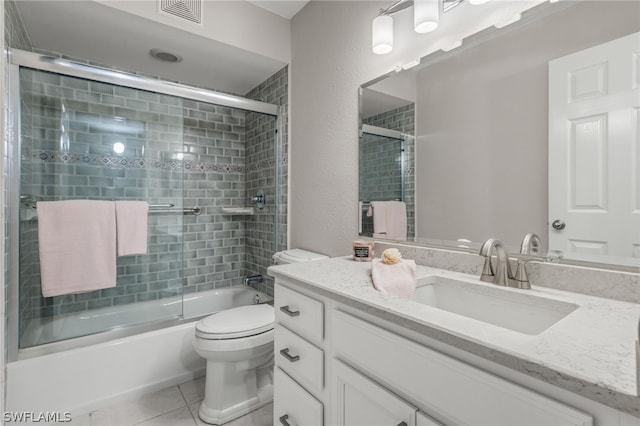 full bathroom featuring tile patterned floors, vanity, toilet, and bath / shower combo with glass door