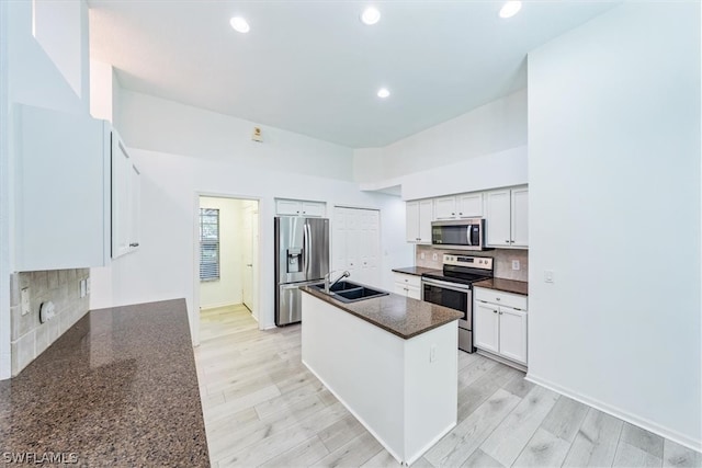 kitchen with a kitchen island, appliances with stainless steel finishes, white cabinets, backsplash, and sink