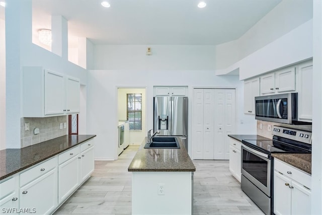 kitchen featuring tasteful backsplash, stainless steel appliances, dark stone countertops, a kitchen island, and sink