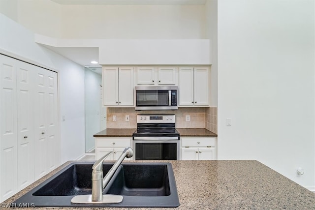 kitchen featuring stainless steel appliances, white cabinets, stone countertops, sink, and tasteful backsplash