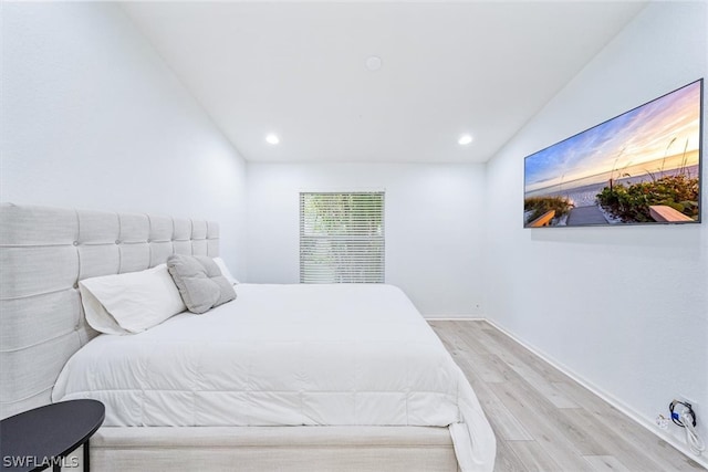 bedroom with vaulted ceiling and light wood-type flooring